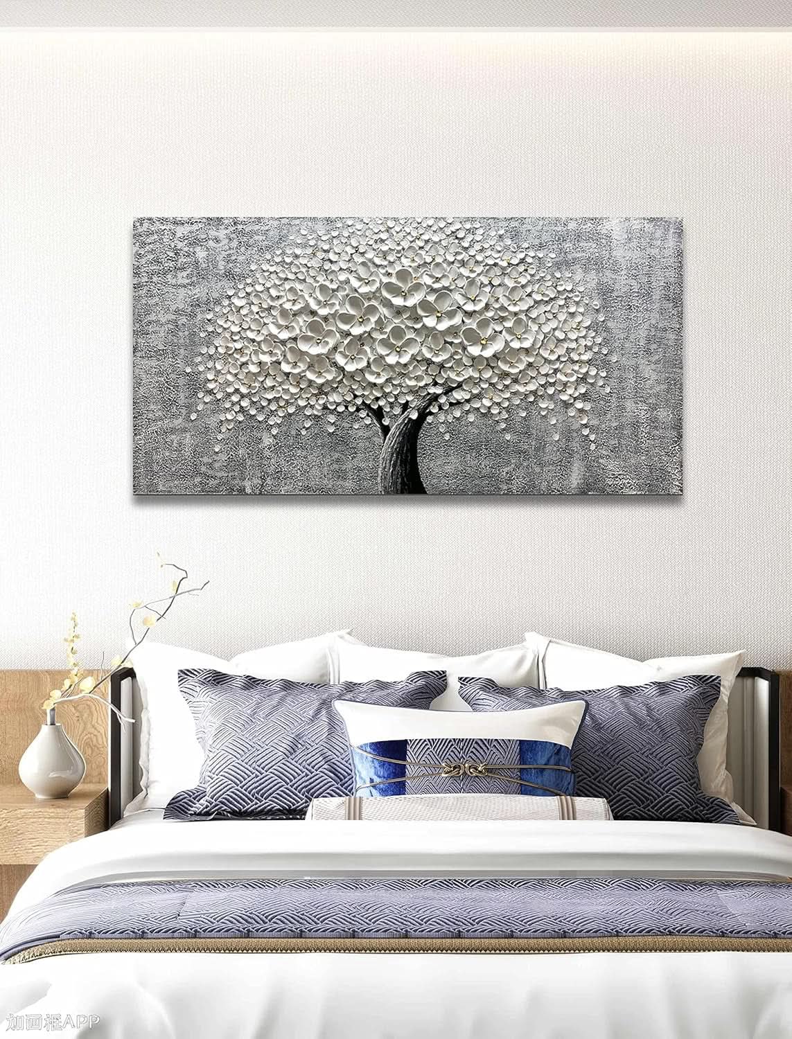 Decorative wall art of a tree with white flowers above a bed in a bedroom.