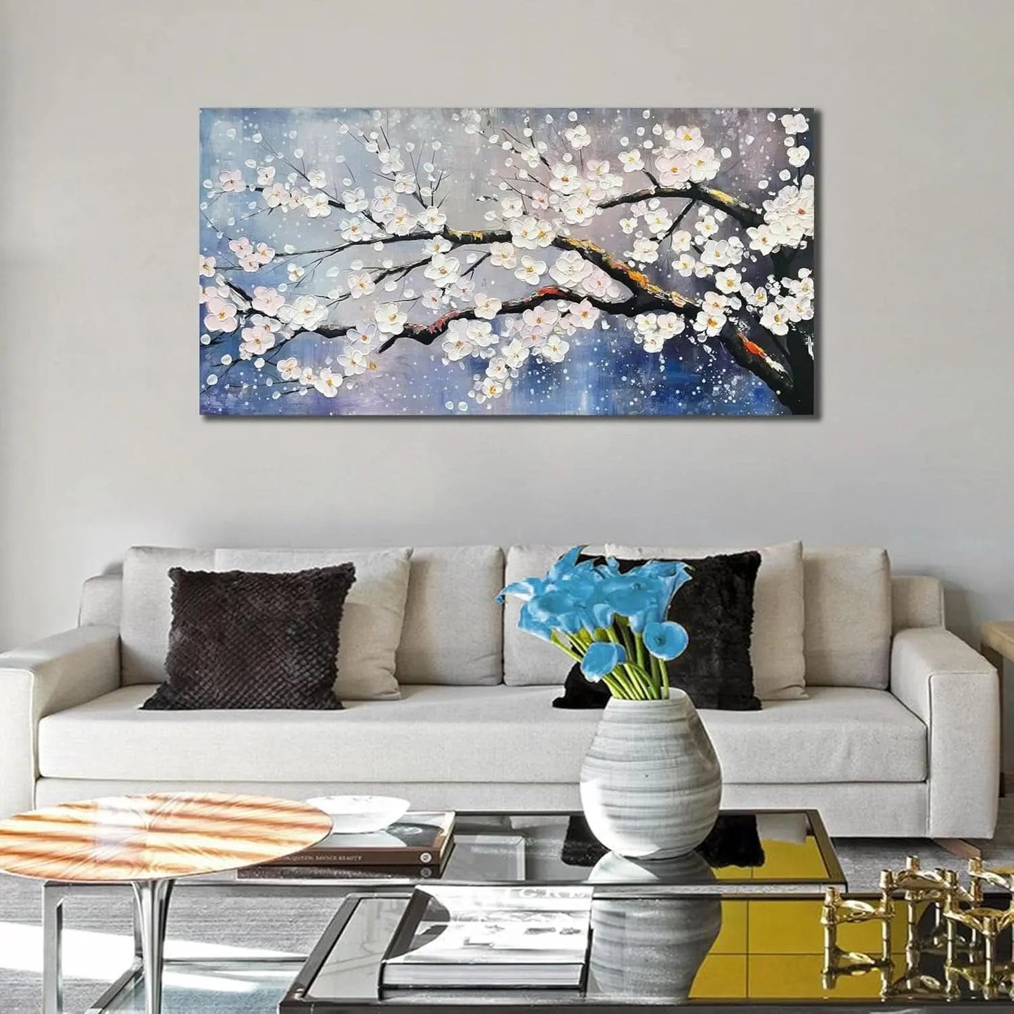 Living room with a large abstract painting of cherry blossoms on the wall above a sofa.