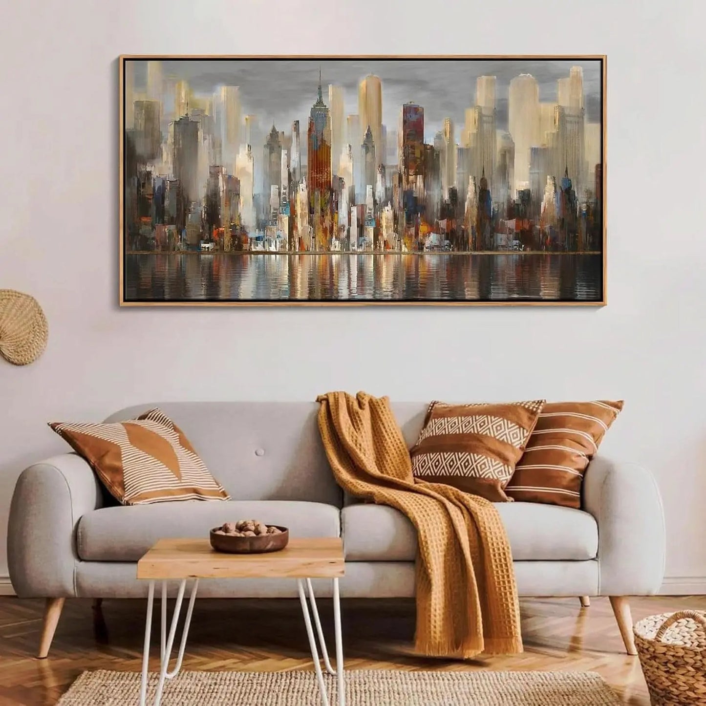 Living room with a cityscape painting above a sofa with decorative pillows and a blanket.