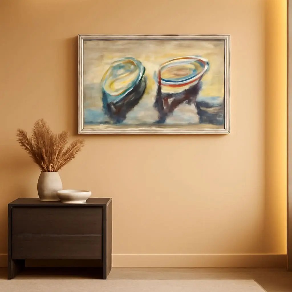 A framed abstract painting of two boats hangs on a warm beige wall above a dark wood side table with a vase of dried grass and a small bowl.