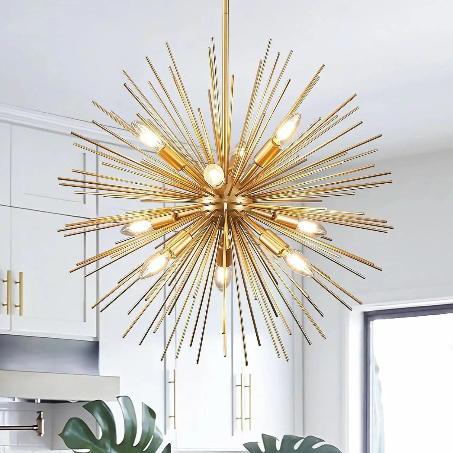 Gold sputnik chandelier hanging in a room with white walls and a plant.
