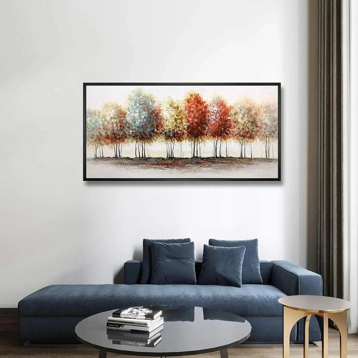 Modern living room with a blue sofa, round coffee table, and framed artwork of trees on the wall.