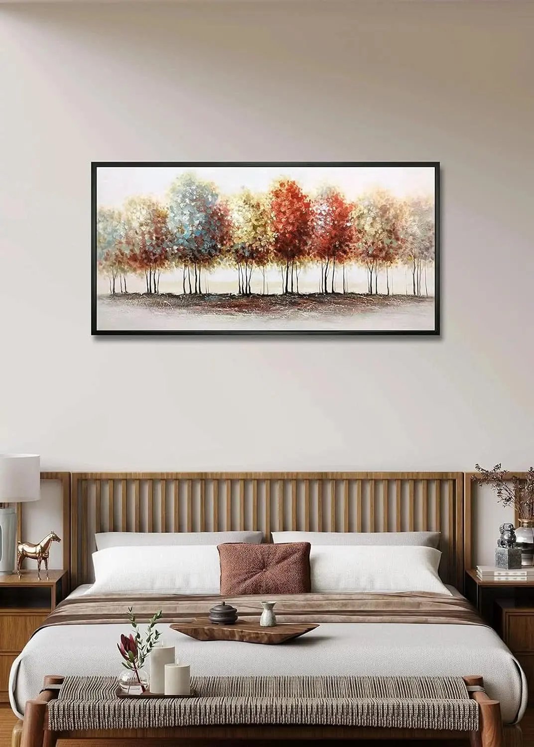 Framed artwork of trees with autumn colors above a bed in a bedroom.