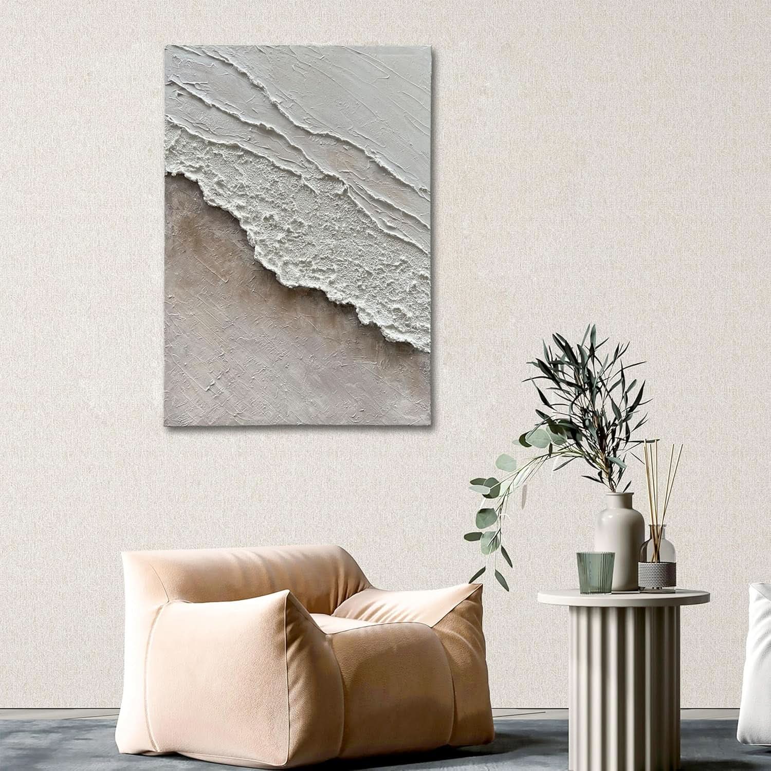 Beige armchair in a room with a large abstract painting on the wall and a small table with plants.