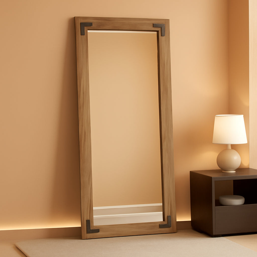 Wooden floor mirror against a beige wall with a side table and lamp.
