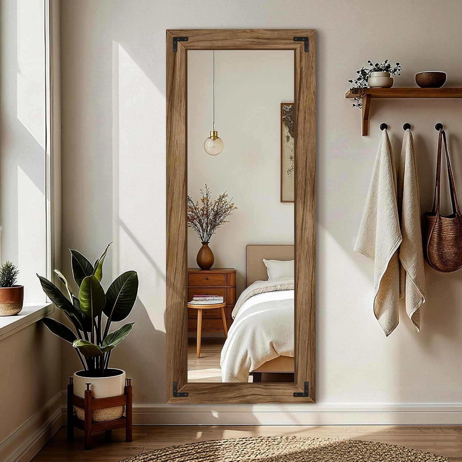 Wooden floor mirror in a bedroom setting with plants and a bed.