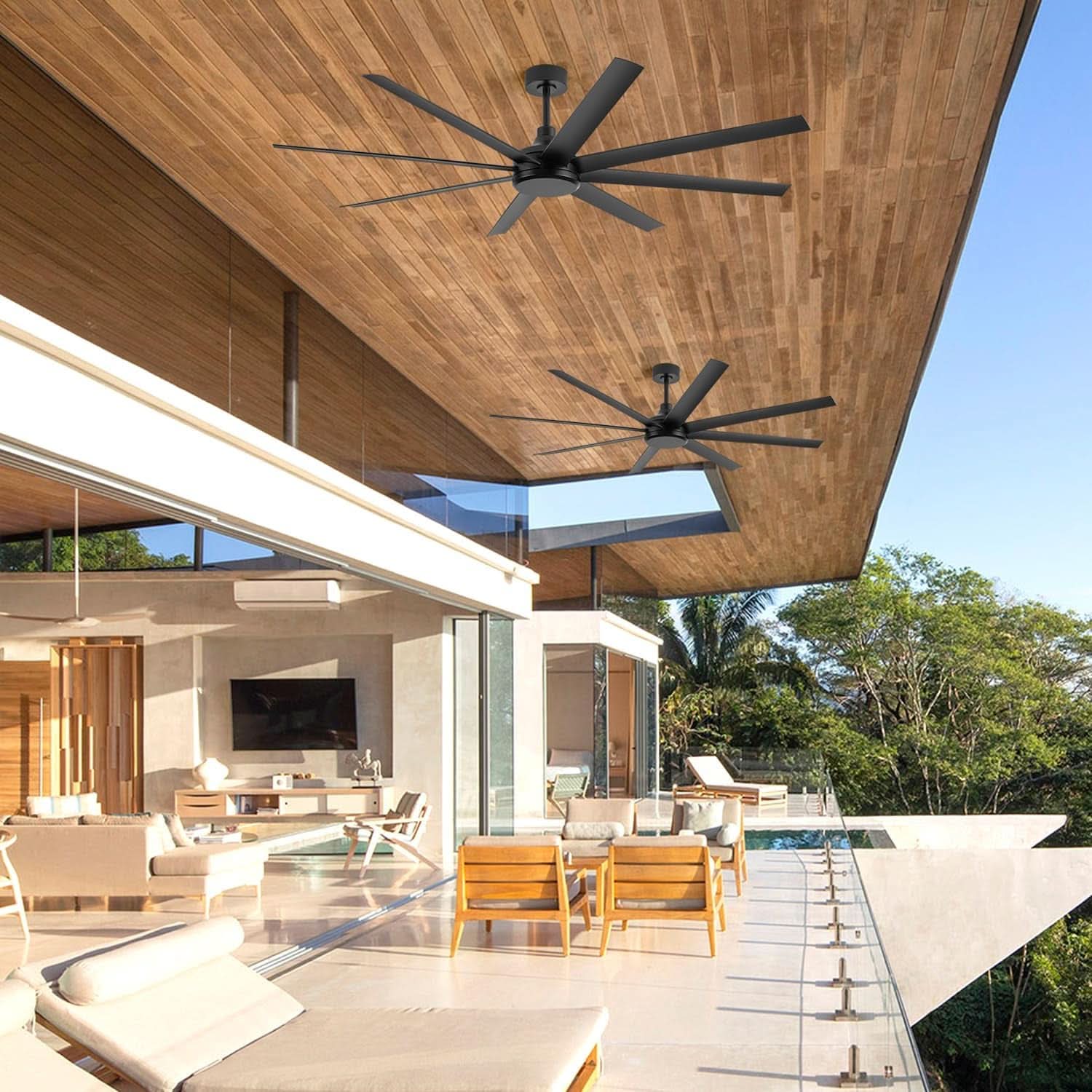 Modern outdoor living space with ceiling fans, furniture, and a view of trees.