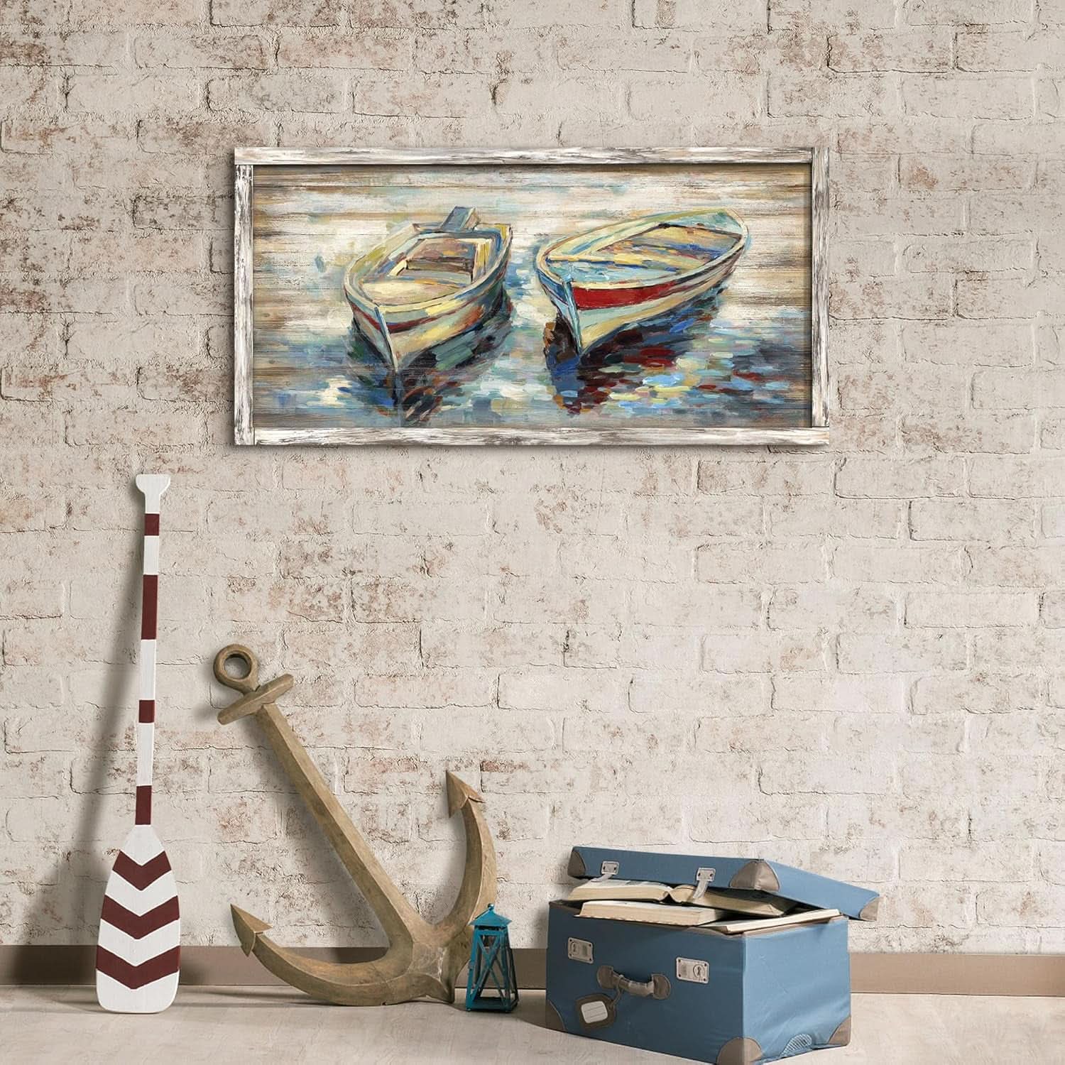 Framed painting of two boats on a brick wall with an anchor and oar below.