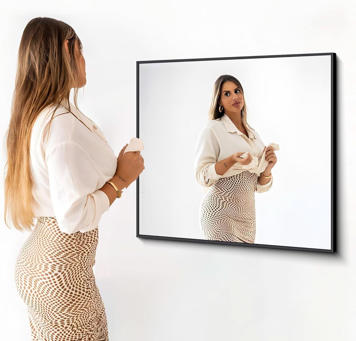 Woman looking at a large mirror on a white wall