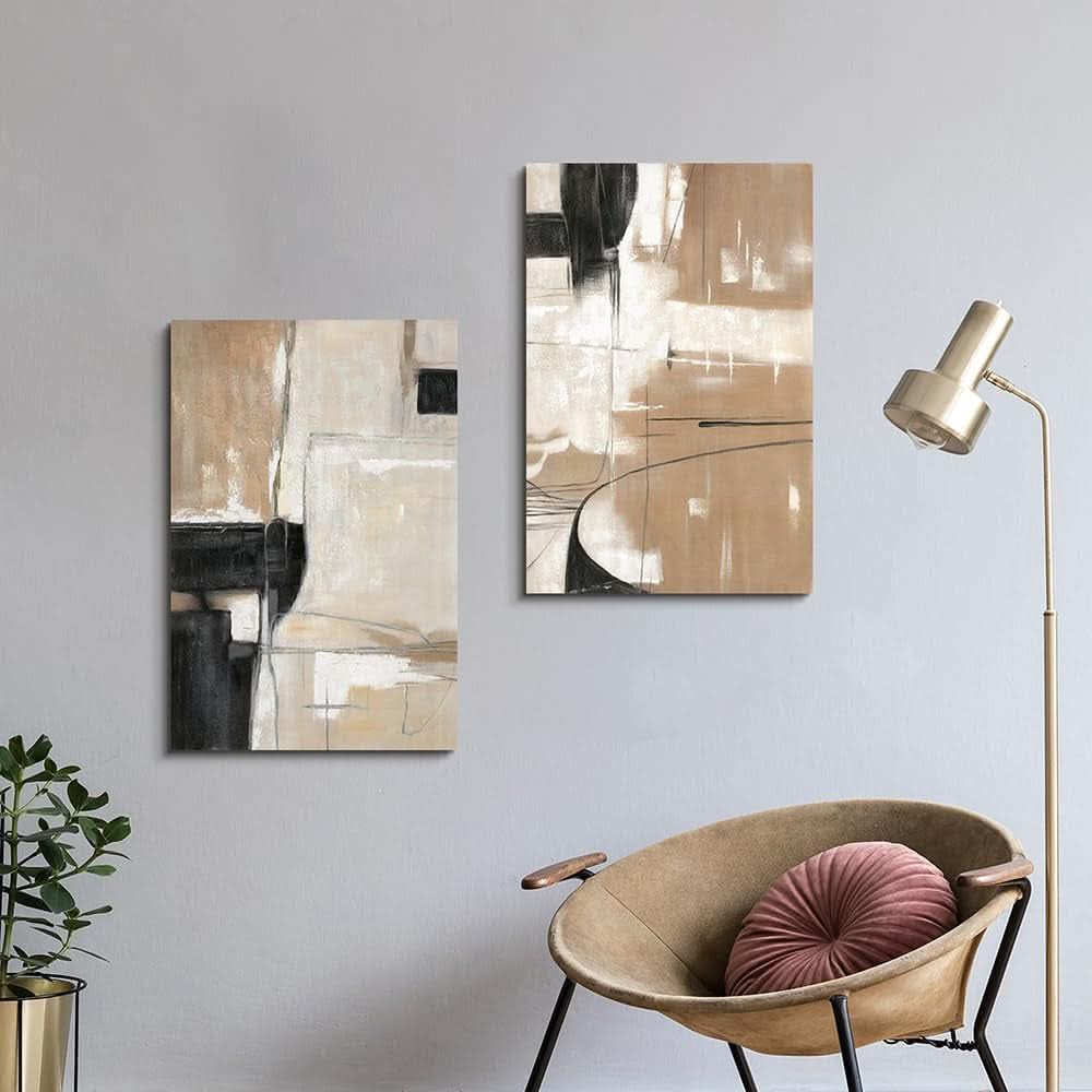 Two abstract art pieces on a wall above a chair with a pink pillow and a floor lamp.