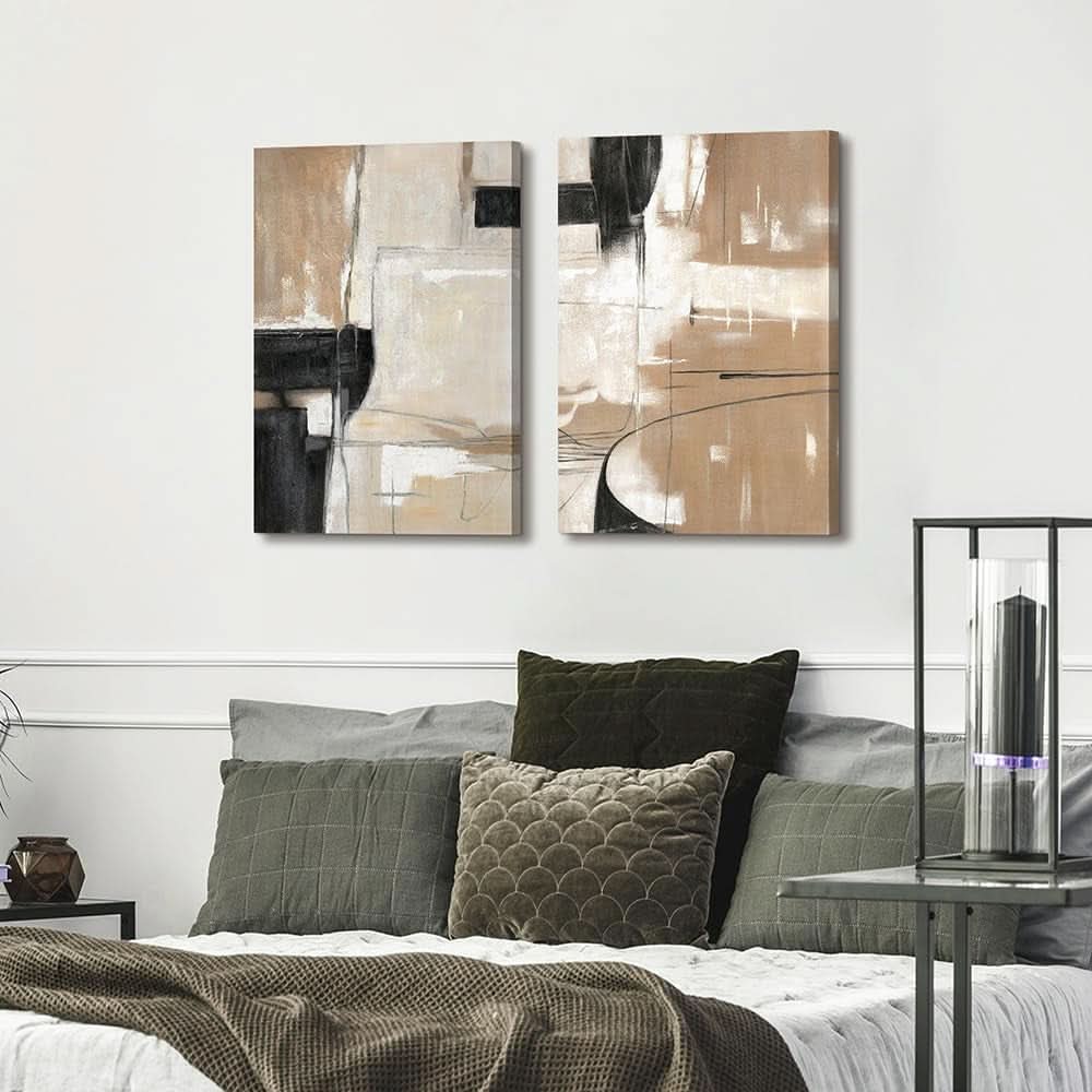 Two abstract art pieces on a wall above a bed with decorative pillows.
