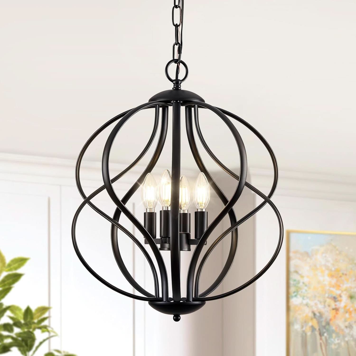 Black metal pendant light fixture in a room with a painting and plant.