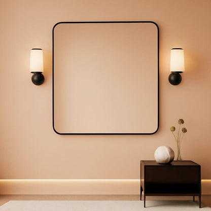 Modern interior with a large square mirror on a beige wall, flanked by two wall sconces.
