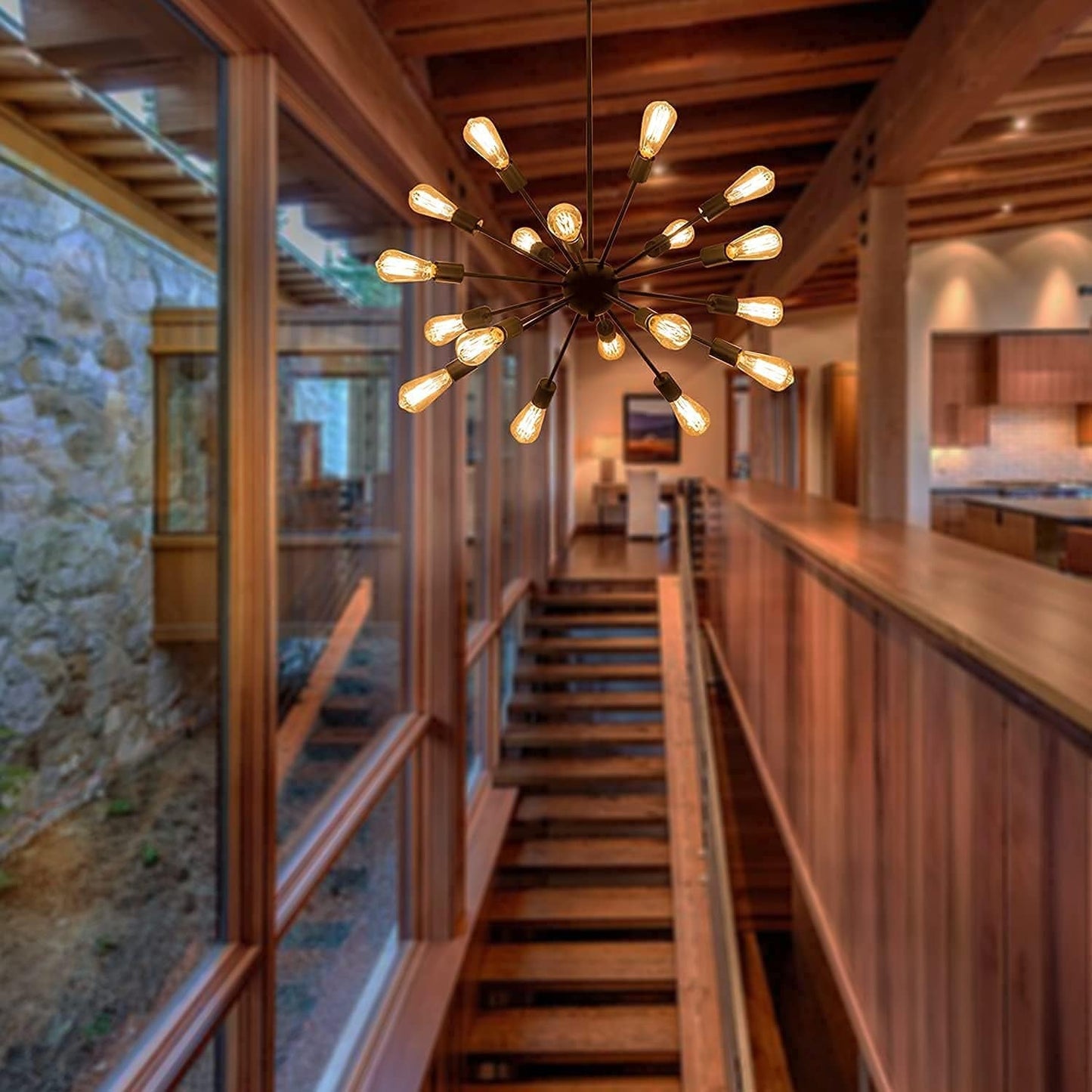 A modern multi-light sputnik chandelier with warm Edison-style bulbs hangs over a wooden staircase in a rustic, wood-paneled interior.