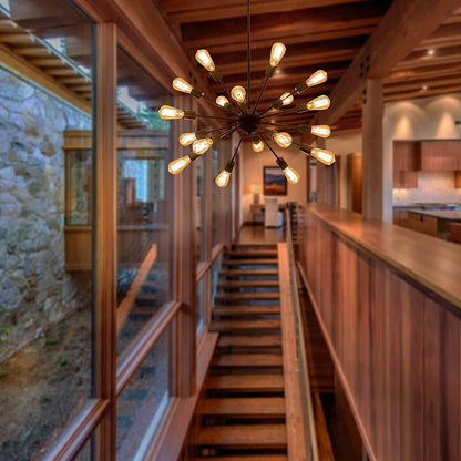 A modern multi-light sputnik chandelier with warm Edison-style bulbs hangs over a wooden staircase in a rustic, wood-paneled interior.