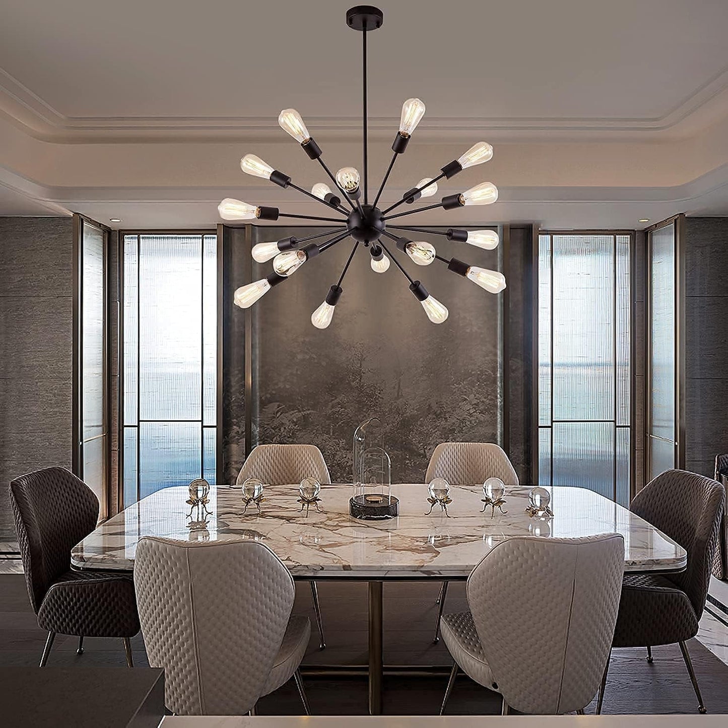A modern multi-arm sputnik chandelier with clear glass globe bulbs hangs over a marble dining table in a contemporary dining room with gray textured walls and tall windows.