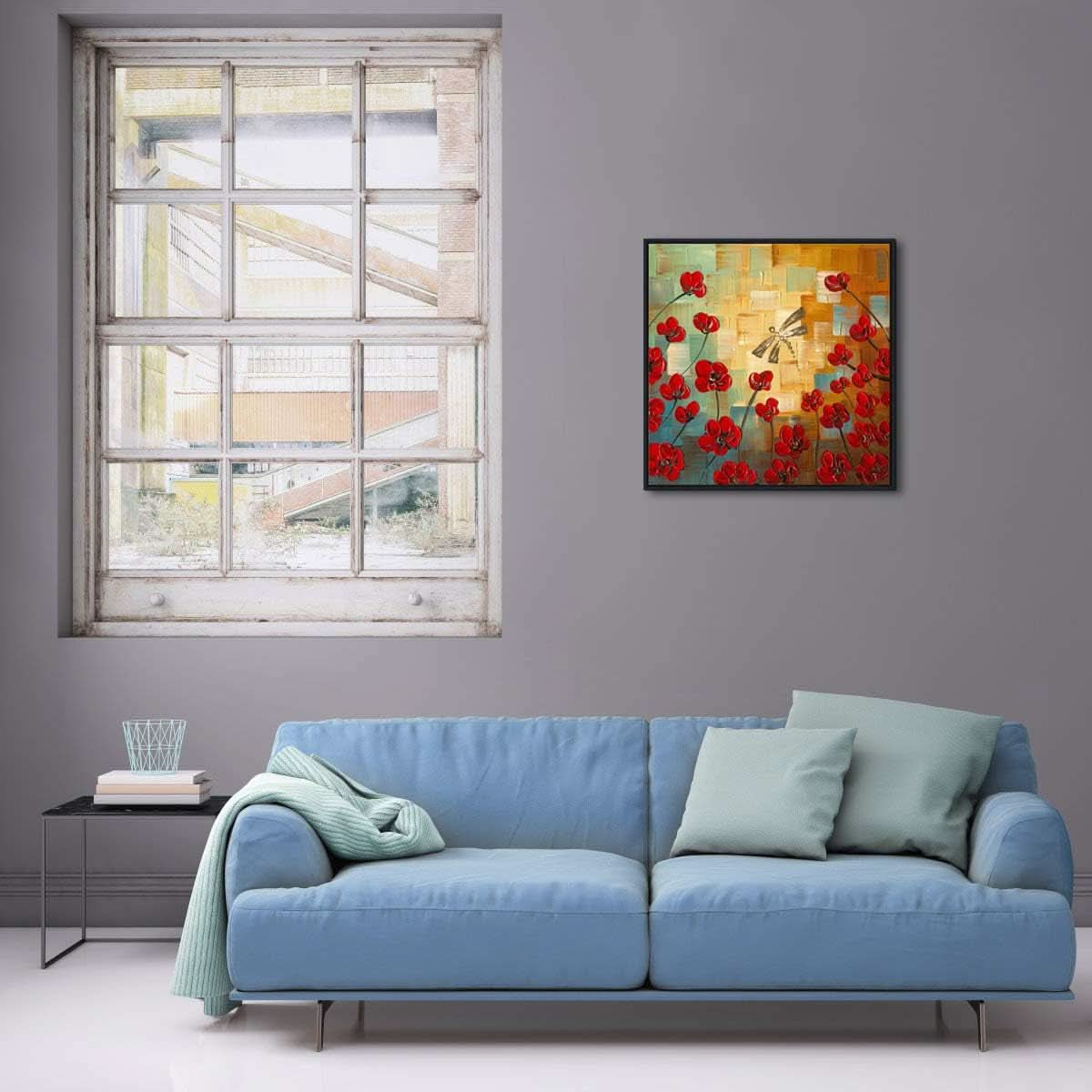Living room with a blue sofa, a painting of red flowers on the wall, and a window.