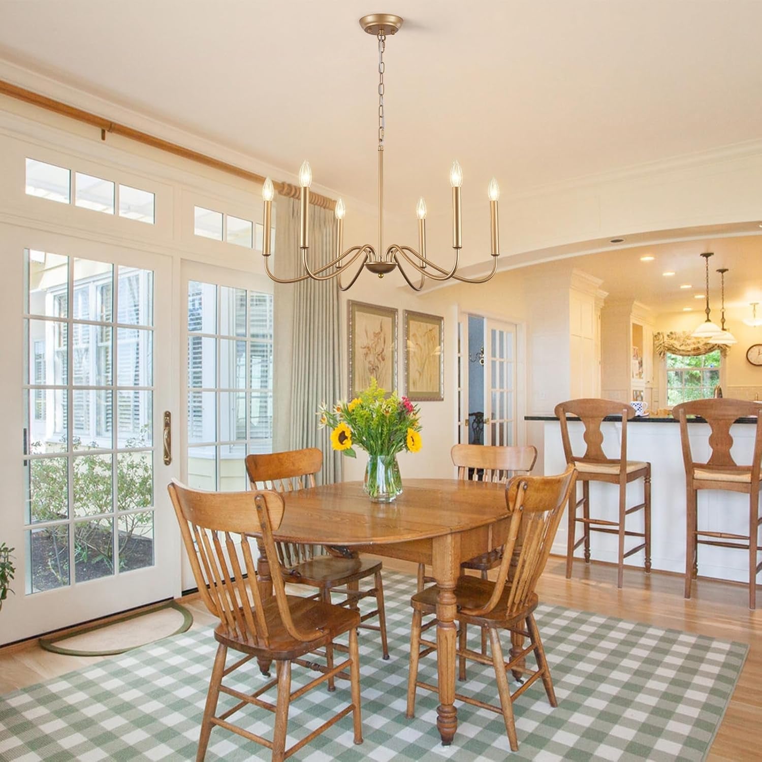 Dining room with wooden table and chairs on a checkered rug, large windows, and a chandelier.
