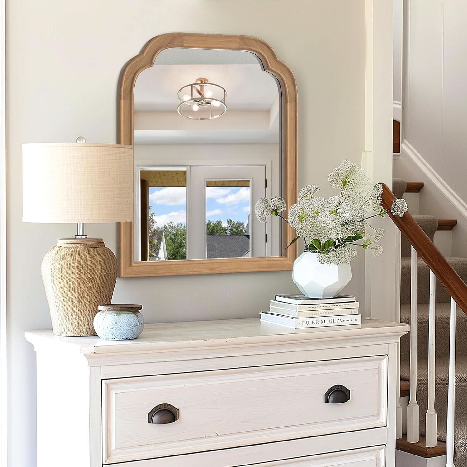 White dresser with mirror, lamp, and decorative items in a home setting