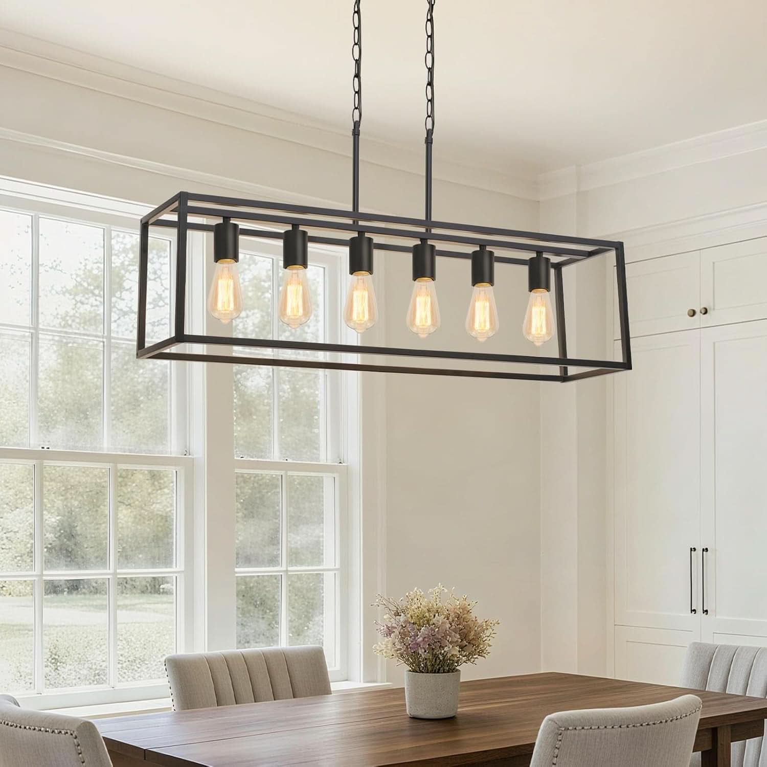 Modern black rectangular chandelier hanging above a dining table with natural light coming through a window.