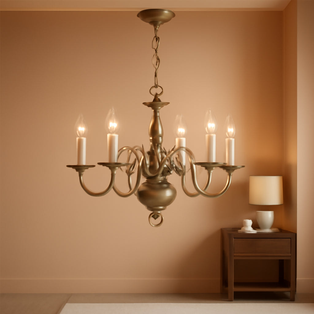 Gold chandelier hanging in a room with a side table and lamp.